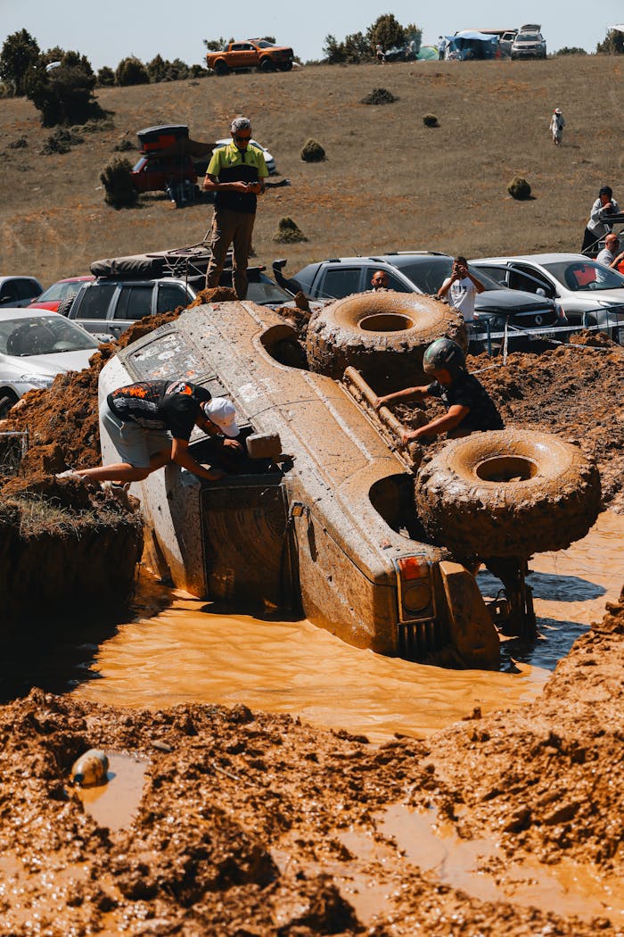 Rescue operation for an overturned vehicle in muddy terrain during an offroad adventure.