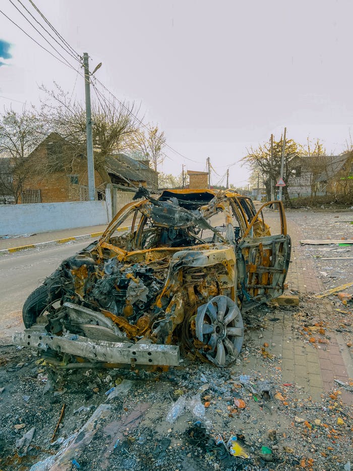 A burnt and wrecked vehicle on a street in Borodyanka, showcasing urban destruction.